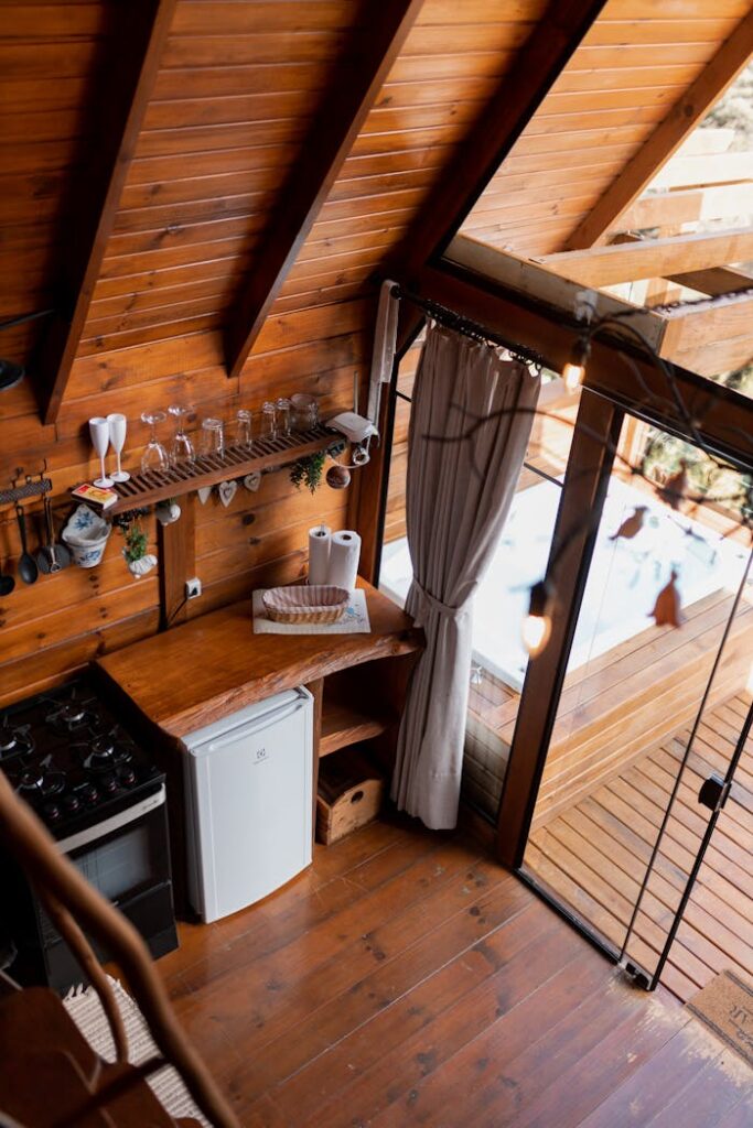 Wooden cabin kitchen interior with natural light and rustic decor.